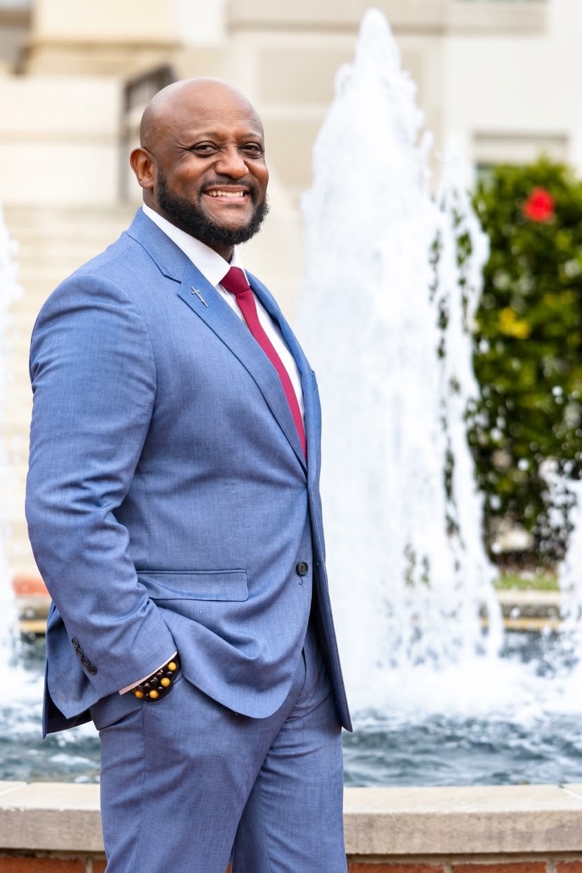 Dr. Curtis Williams in a blue suit beside a fountain